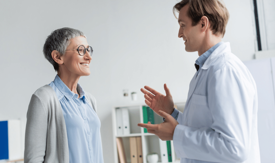 MLadi liječnik razgovara s nasmijanom starijom pacijenticom