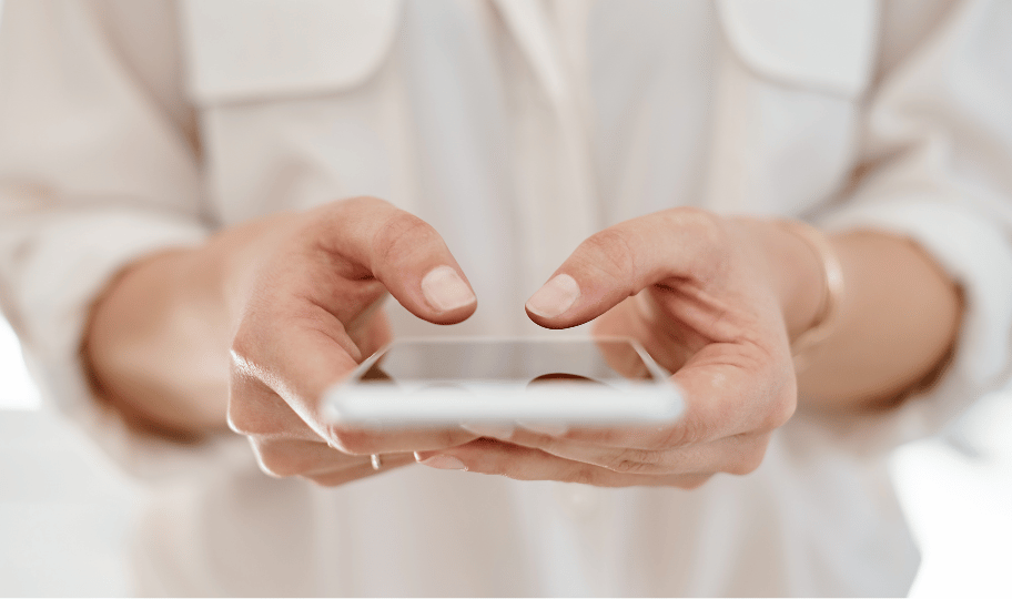 Krupni kadar žene u bijeloj košulji koja drži pametni telefon