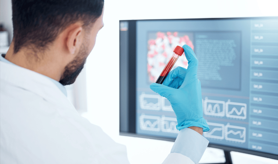 Laboratorijski tehničar pred ekranom promatra ampulu krvi