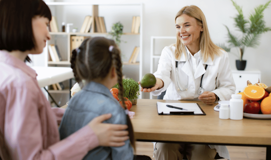 Liječnica nudi voćku djevojčici koja je došla na pregled s majkom