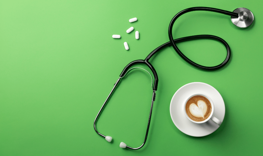 Stetoskop, tablete i šalica kave s mlijekom na zelenoj podlozi