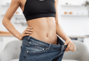 žena koja demonstrira koliko su joj hlače prevelike zbog mršavljenja