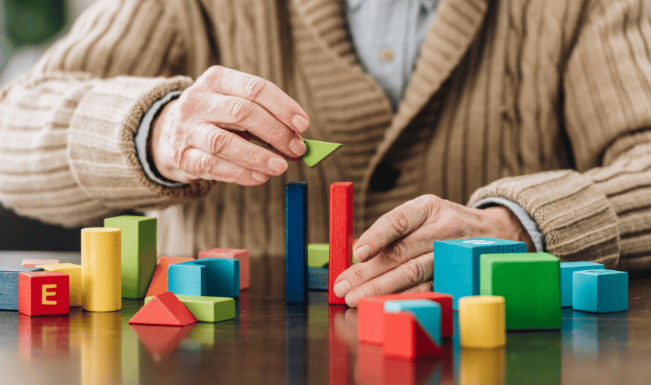 stariji muškarac slaže šarene drvene kockice