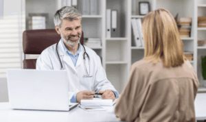 Liječnik razgovara s pacijenticom za stolom u ordinaciji