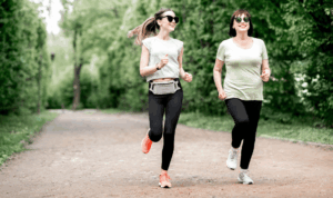 Starija i mlađa žena trče po šumskoj stazi
