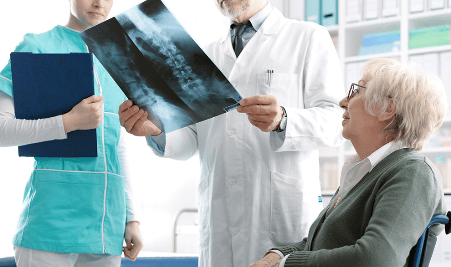liječnik i sestra pregledavaju rendgenske snimke starije pacijentice u kolicima