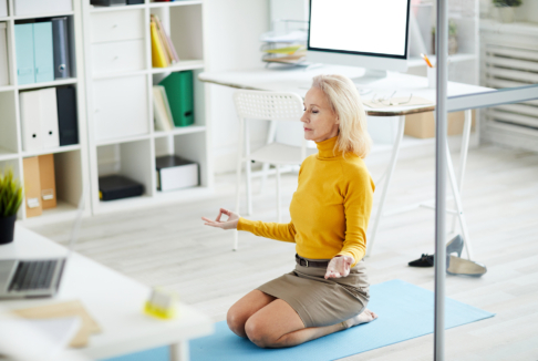 starija žena meditira na podu u uredu