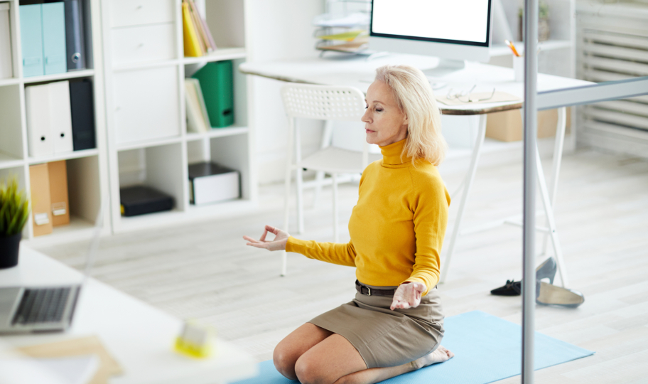 starija žena meditira na podu u uredu