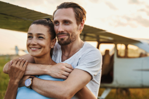 mladi nasmijani par se grli i gleda u daljinu