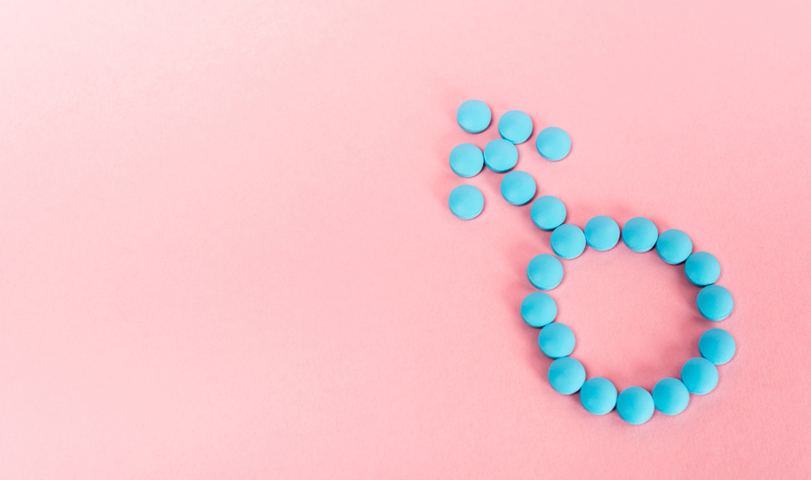 Simbol muškog spola načinjen od plavih pilula na ružičastoj pozadini