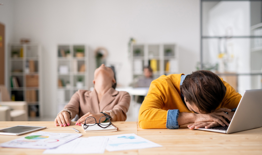 Dvoje umornih ljudi sjedi za radnim stolom