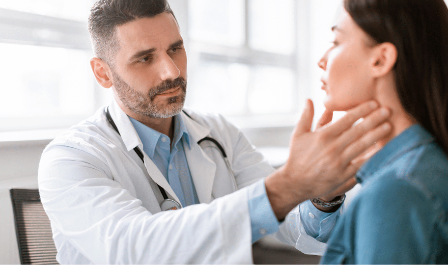 Muški liječnik s bradom pregledava štitnjaču mlade žene