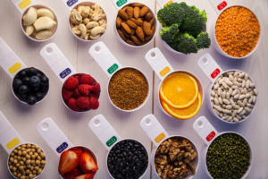 Različite zdrave namirnice u identičnim posudicama, pravilno posložene na drvenom stolu