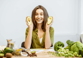 nasmijana m,alda žena s naimirnicam koje podržavaju zdravo starenje oko sebe, u rukama drži avokado