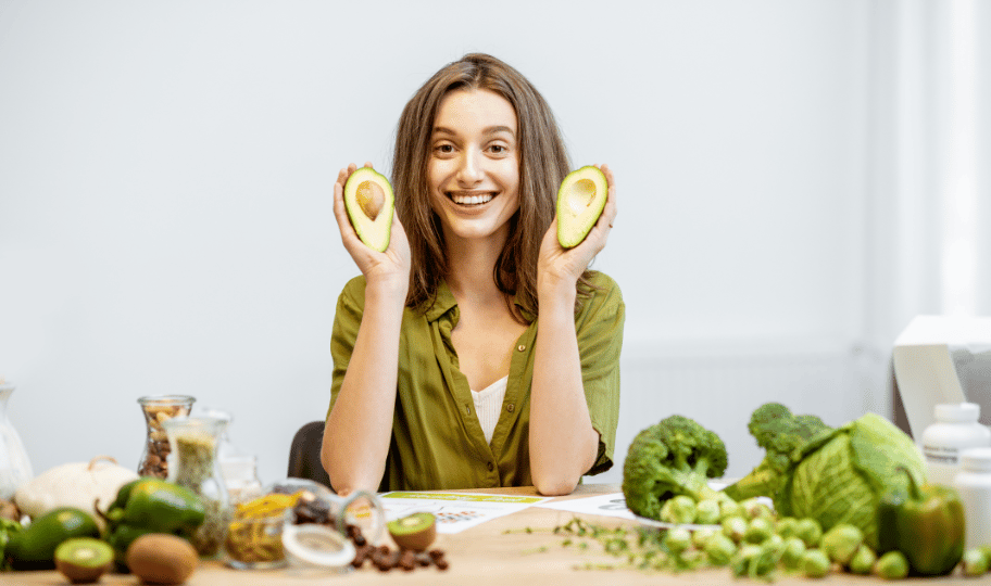 nasmijana m,alda žena s naimirnicam koje podržavaju zdravo starenje oko sebe, u rukama drži avokado