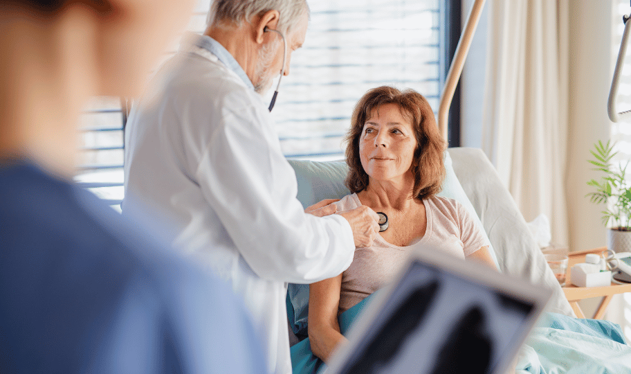 liječnica slulša srce žene u menopauzi koja leži u bolničkom krevetu
