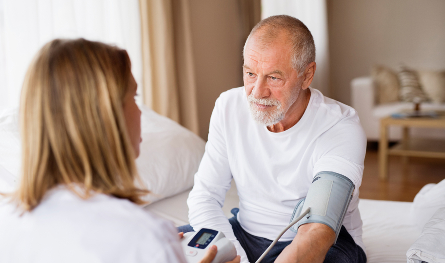 Medicinska sestra pomaže starijem muškarcu izmjeriti tlak