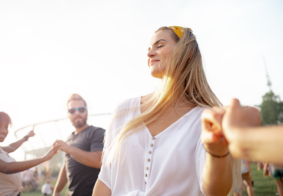 mlada sretna žena duge plave kose pleše s prijateljima na otvorenom