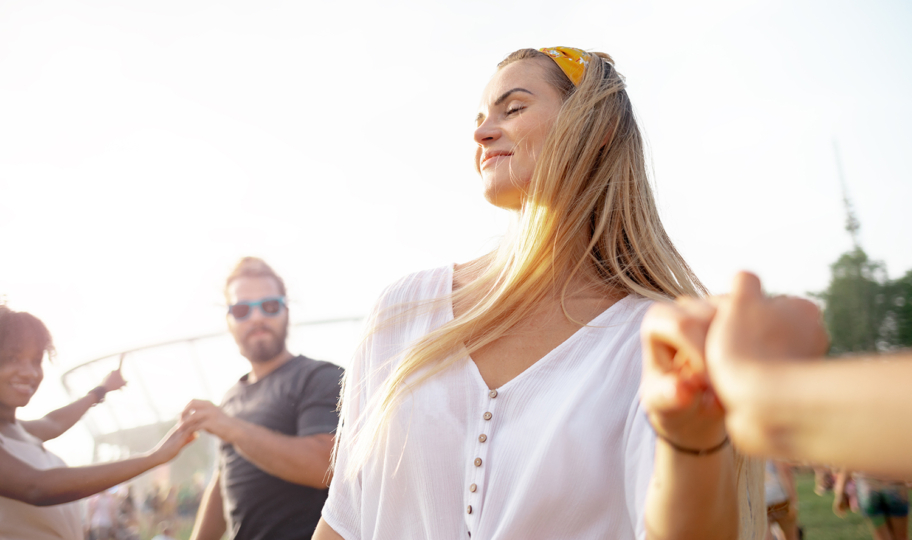 mlada sretna žena duge plave kose pleše s prijateljima na otvorenom