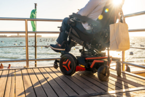 pogled s leđa na osobu u električnim invalidskim kolicima koja gleda u more