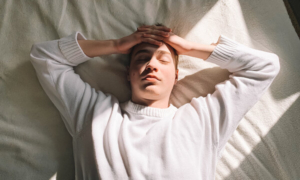 umorni muškarac leži u krevetu na leđima po danu