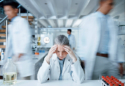 laboratorijak tehničarka pod stresom sjedi u laboratoriju i drži se za glavu, burnout