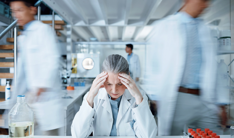 laboratorijak tehničarka pod stresom sjedi u laboratoriju i drži se za glavu, burnout