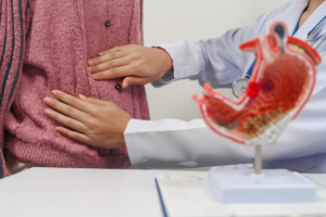 liječnica prepipava trbuh pacijenta s modelom želuca u prednjem planu