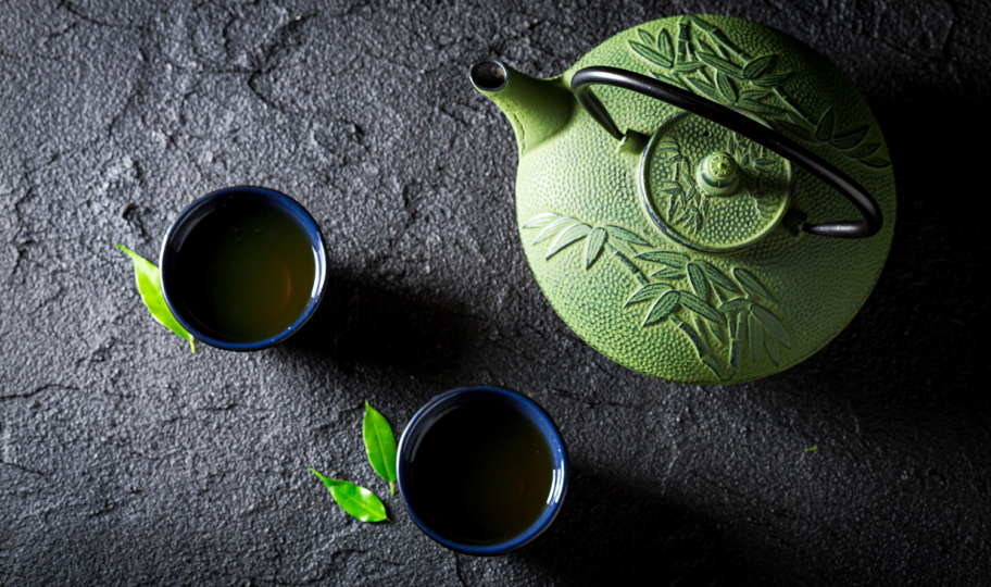dvije šalice čaja i zeleni čajnik od gusa