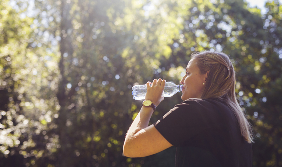 sunčan ljetni dan, žena pije vodu iz plastične bočice