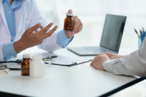 krupni karad ruku liječnika koji pacijentu objašnjava koliko tableta treba popiti