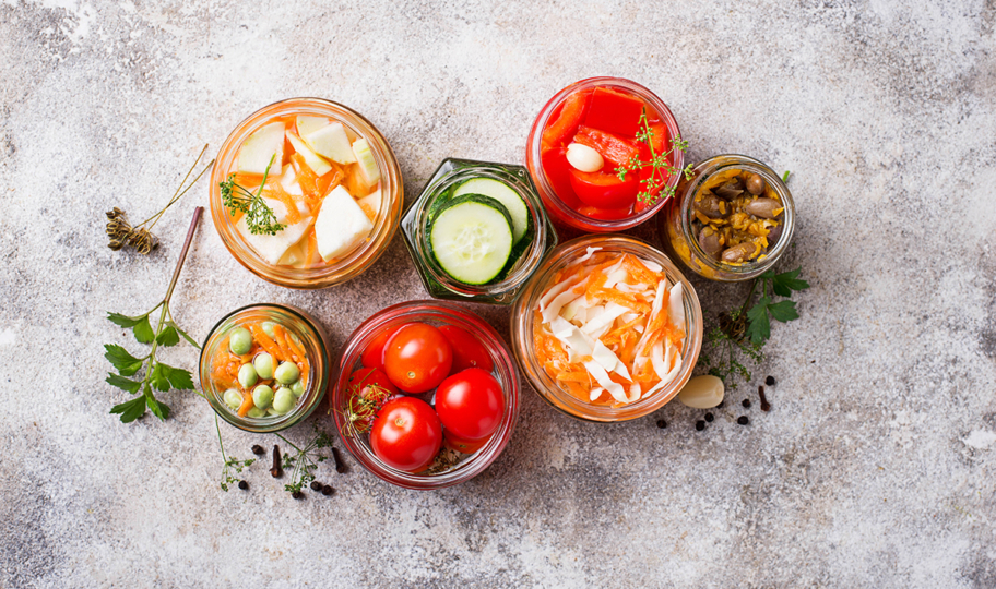 razne fermentirane namirnice u teglicama na sivoj podlozi