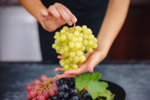 krupni kadar ženskih ruku koje drže grozd bijelog grožđa
