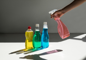 krupni kadar ruke koja drži sredstvo za čišćenje i još tri boce sličnih sredstava pokraj