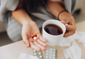 krupni kadar ženskih ruku koje drže šalicu kave i razne tablete