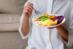 krupni kadar žene u bijeloj košulji koja u ruci drži tanjur povrća