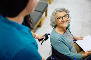 nasmijana pacijentica u kolicima koja vozi medicinska sestra