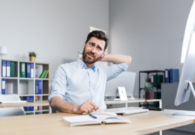 dekoncentrirani, zbunjeni muškarac sjedi za radnim stolom