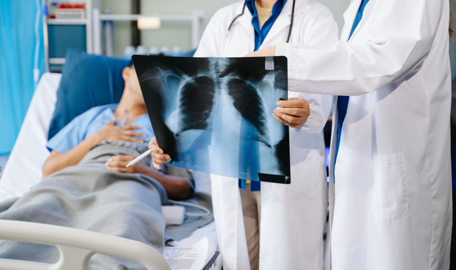liječnik proučava rengdgen pluća pacijenta koji leži u bolničkom krevetu