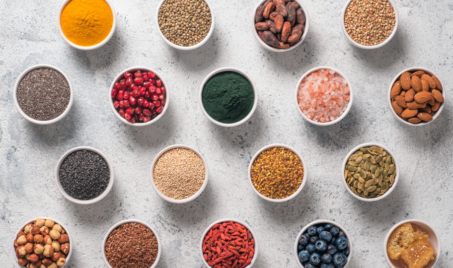 razne superfood namirince u keramičkim zdjelicama na kamenoj podlozi