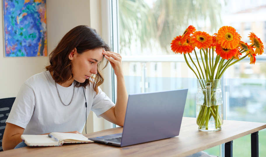 mlada žena sjedi i radi za računalom, ali je muči moždana magla
