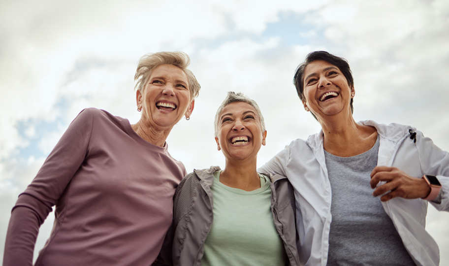 tri sretne, nasmijane, zagrljene žene srednje dobi