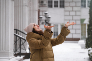 mlada žena se veseli pahuljama snijega