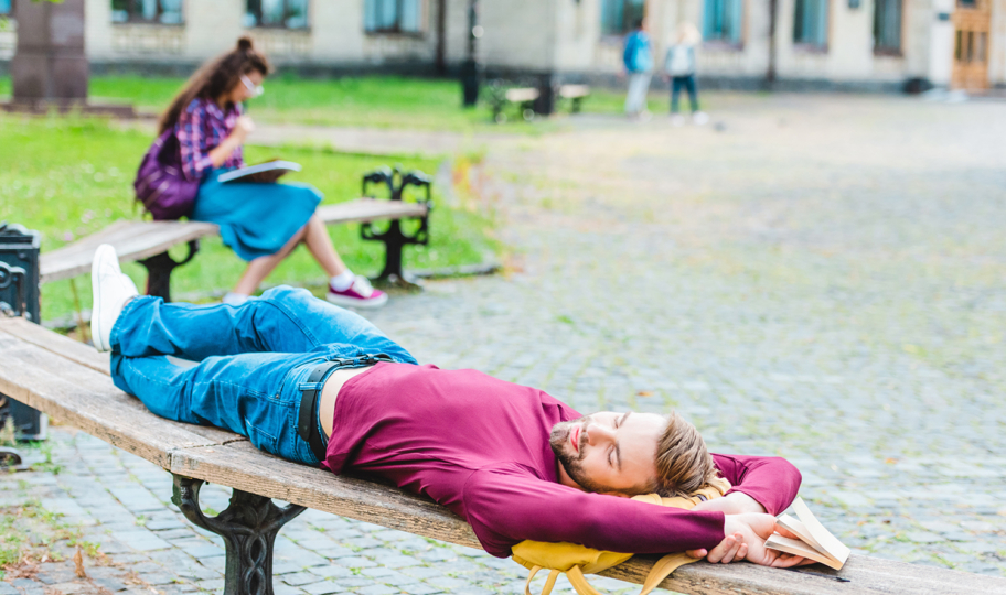 stedent drijema na klupici u parku