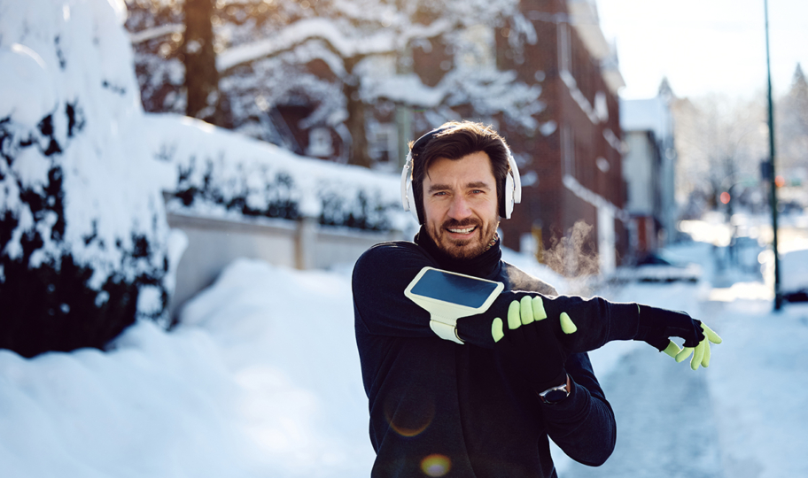 nasmijani muškarac se razgibava prije trčanja po snijegu