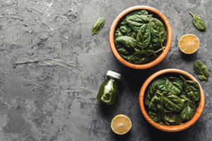 zeleno lisnato povrće i bočica zelenog soka kao namirnice za prevenciju raka