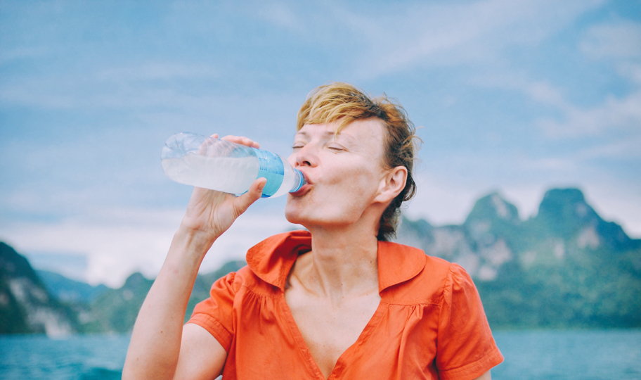 žena u planinama pije vodu iz bočice