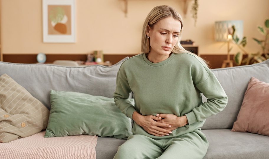 portret plavokose žene na kauču koju boli želudac