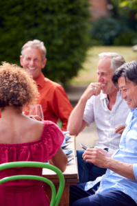 društvo dobro raspoloženih ljudi srednjih godina sjedi za stolom naotvorenom