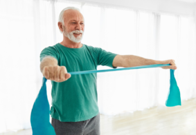 Stariji muškarac u svijetloj prostoriji rasteže elastičnu traku